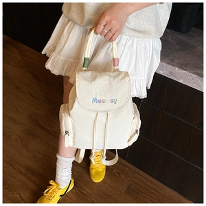 Detail view of a creamy white nylon backpack with MeaRey embroidery and drawstring