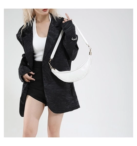 Detail of white moon-shaped crossbody bag with glossy leather and gold hardware on model