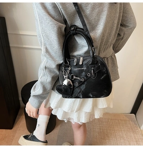 Détail d'un sac bandoulière noir en forme de coquille avec chaîne et cœur