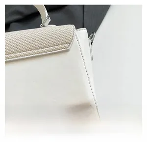 Detail of beige shoulder bag showing woven texture and smooth faux leather finish