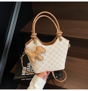 Détail du sac seau imprimé avec poignée nouée marron et breloque chien sur escalier