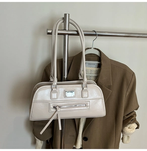 Vue détaillée du sac d'épaule en cuir verni beige avec fermeture éclair et fines anses