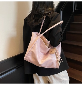 Detail of pink large faux leather tote bag with cute bear charm and tassel ornament