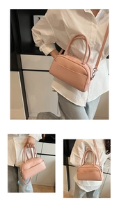 Detail of a minimalist pink leather Boston bag with top handles and adjustable strap