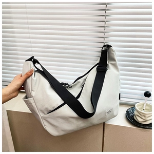 Detail of minimalist cream crossbody dumpling bag with MS logo and adjustable strap