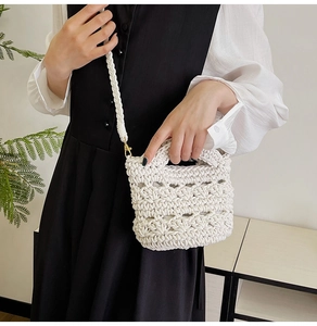 Close-up of the intricate woven hollow texture and metallic hook on the white handbag
