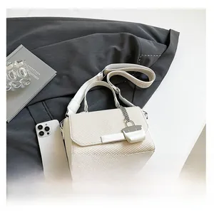Detailed close-up of white woven leather handbag on a grey suit background