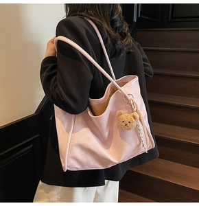 Pink large capacity faux leather tote bag with teddy bear pendant shown on model