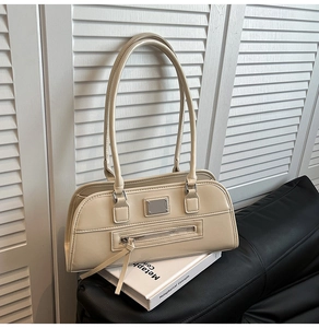 Détail de sac porté épaule beige vintage avec plaque argentée et long gland de fermeture