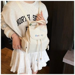 Side view of cream nylon mini backpack with embroidered logo and drawstring closure