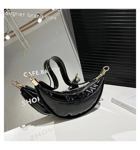 Detail of black crescent bag featuring shiny patent leather pleats and gold hardware