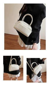 Detail view of a minimalist cream shoulder bag paired with a professional black blazer outfit