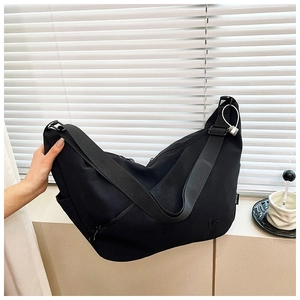 Detail of black nylon dumpling bag featuring adjustable wide strap and side pocket storage