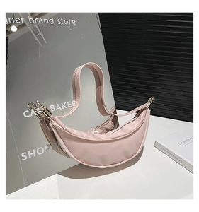 Detailed mirror view of pink crescent shoulder bag with metallic zipper and wide strap