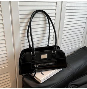 Détail du sac sous le bras en cuir verni noir brillant avec finitions argentées sur cuir