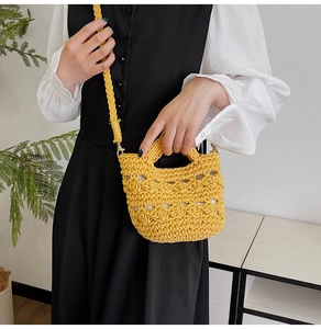 Detailed shot of yellow hand-woven mini bucket bag with hollow crochet texture and shoulder strap