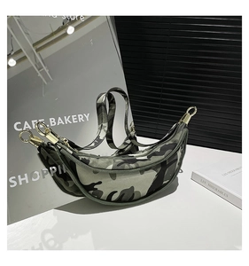 Detail of camouflage crescent bag with gold hardware and adjustable strap on a mirror background