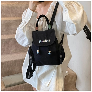 Detail of a black canvas backpack featuring colorful embroidery and drawstring closure