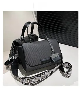 Close-up of woven texture black handbag with geometric pattern strap and metallic chain