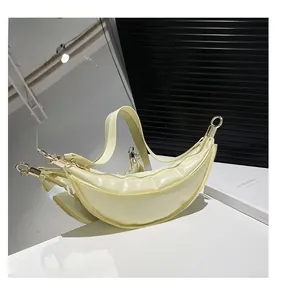 Close-up of a pale yellow glossy croissant bag with gold hardware and mirror reflection