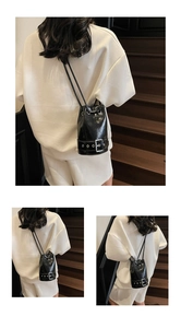 Détail du sac seau en cuir ciré noir avec sangle à boucle argentée et cordon de serrage