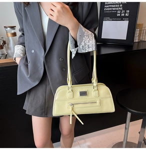 Détail du sac sous le bras en cuir jaune pâle avec plaque argentée dans un café