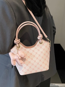 Sac seau rose avec imprimé monogramme floral et breloque chien porté sur un mannequin