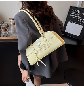 Détail du sac baguette jaune avec fermeture éclair à franges et plaque métallique