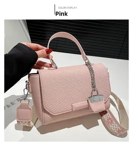 Detail of pink crossbody bag with woven texture, metal chain and patterned wide strap