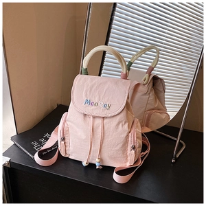 Detail of pink nylon backpack featuring colorful wrapped handles and embroidered flap cover