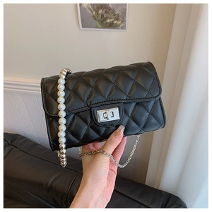 Détail du sac à bandoulière matelassé noir avec chaîne en perles et fermoir rotatif argenté
