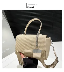 Detail of khaki handbag featuring woven texture and a mini bag charm with wide strap