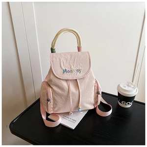 Detail view of pink mini backpack with Mea Rey embroidery and woven cotton handle
