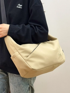 Minimalist beige dumpling crossbody bag with MG logo shown on a person for travel