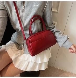 Detail of red leather pillow bag with adjustable shoulder strap worn by a model