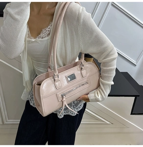 Détail du sac sous le bras rose pâle avec étiquette en métal argenté et gland en cuir