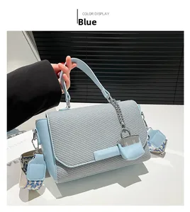 Detail of light blue crossbody bag with woven texture flap and embroidered strap