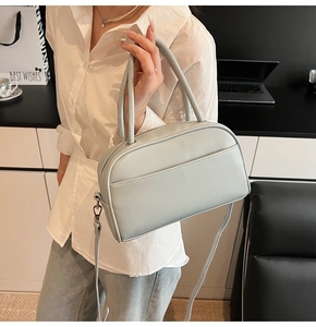 Detail of light grey matte leather pillow bag with double handles and slim shoulder strap