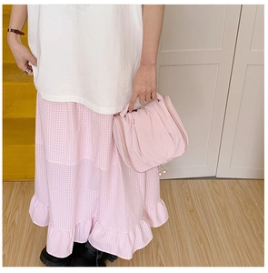 Pink pleated cosmetic bag with pearl zipper detail held by model in home setting