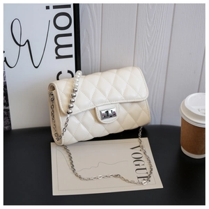 Détail d'un sac bandoulière beige matelassé avec chaîne en perles et fermoir rotatif argent