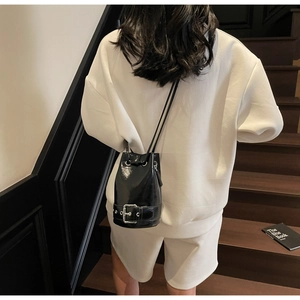 Vue arrière d'un sac seau noir brillant avec une tenue blanche sur des escaliers rétro