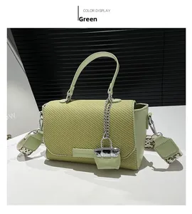 Detailed macro of green crossbody bag showing woven flap texture and wide patterned strap