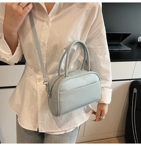 Close-up of light blue Boston bag with matte PU leather held by a model in white