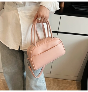 Close-up of light pink leather satchel bag featuring textured finish and metal zippers