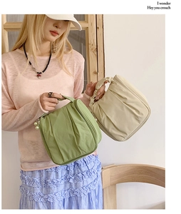 Detail view of stylish pleated cosmetic bags in green and beige with pearl zipper charm