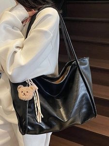 Large black glossy leather tote bag with a cute brown plush bear charm for daily use