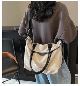 Détail d'un grand sac fourre-tout en toile crème avec poignées en cuir noir et bandoulière