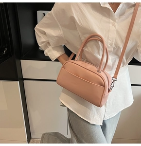 Detail of soft pink Boston style handbag with dual handles and adjustable shoulder strap