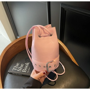 Vue détaillée du sac seau en cuir verni rose avec boucle décorative et bandoulière