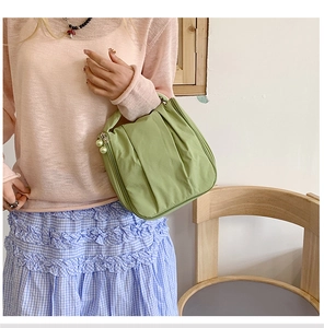 Detail of light green pleated handbag with decorative pearl charms on the zipper slider